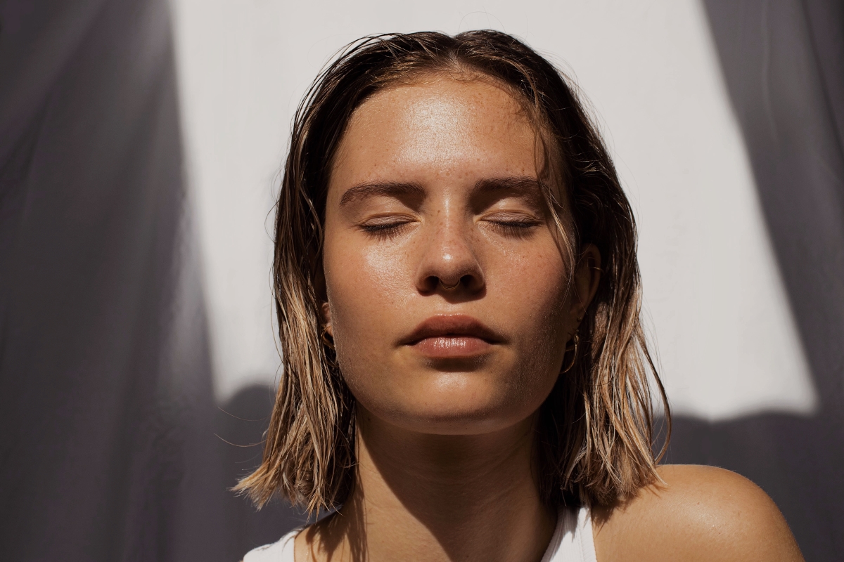 Portrait of a woman while her eyes are closed and the sun in shining on her face